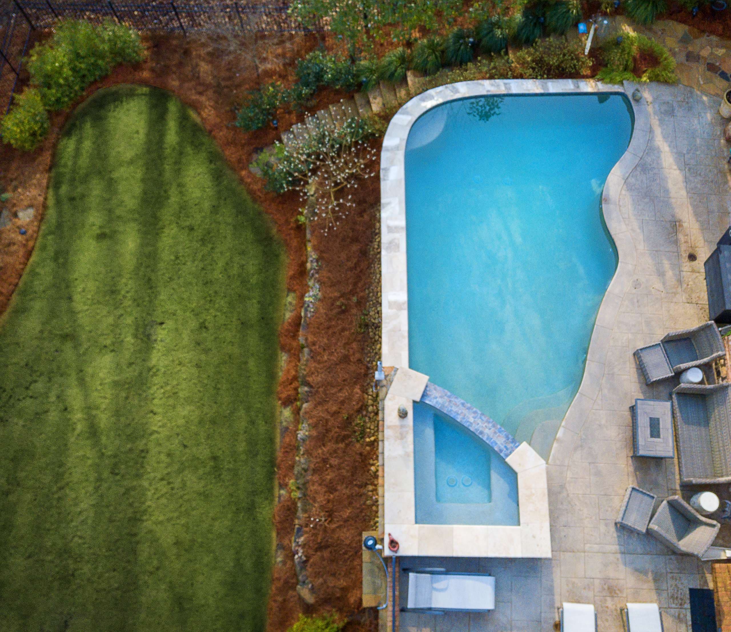 Freeform pool with raised stone retaining wall and stamped concrete deck in Atlanta