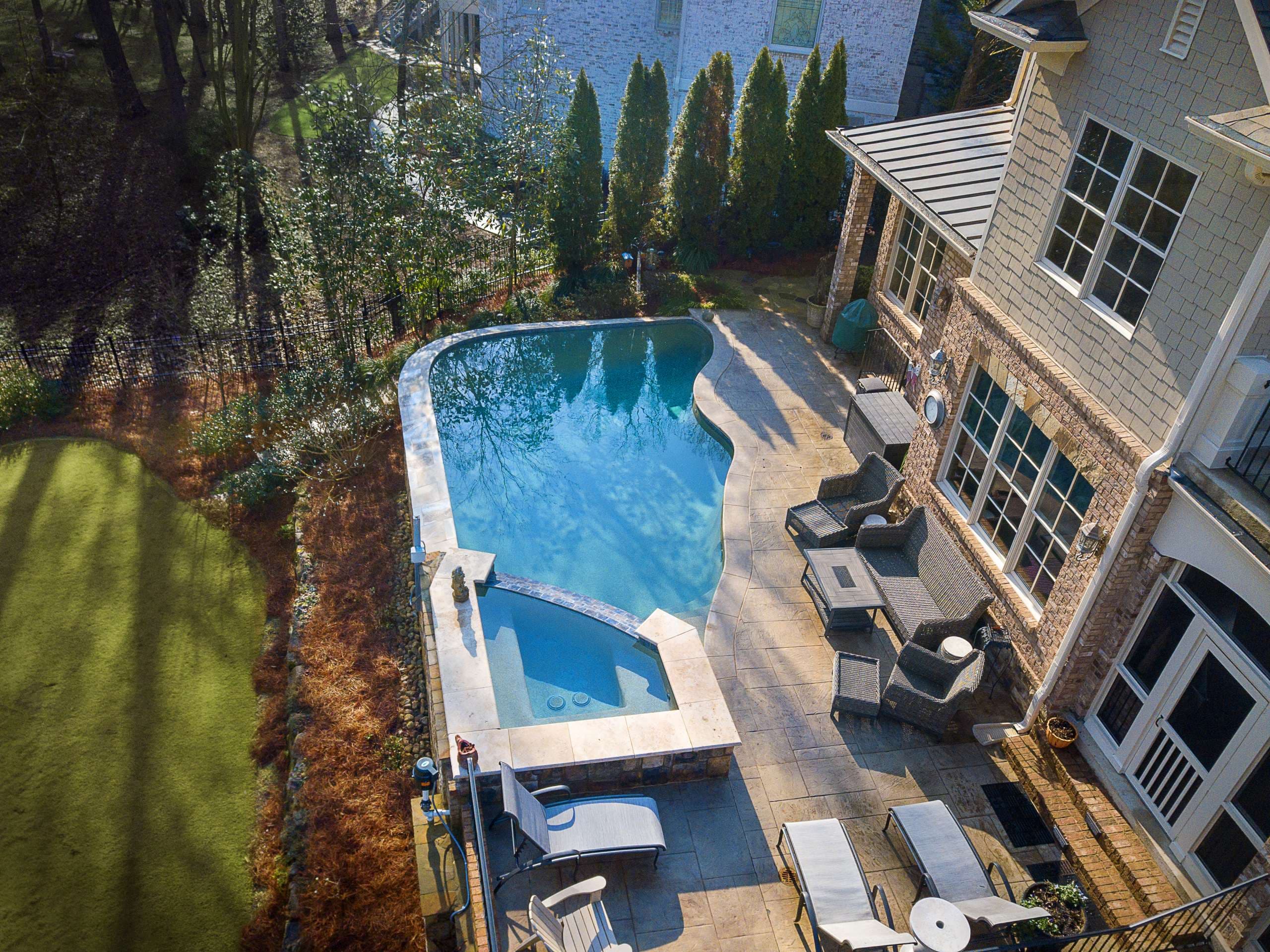 Freeform pool renovation with travertine coping and stone paver deck in Metro Atlanta
