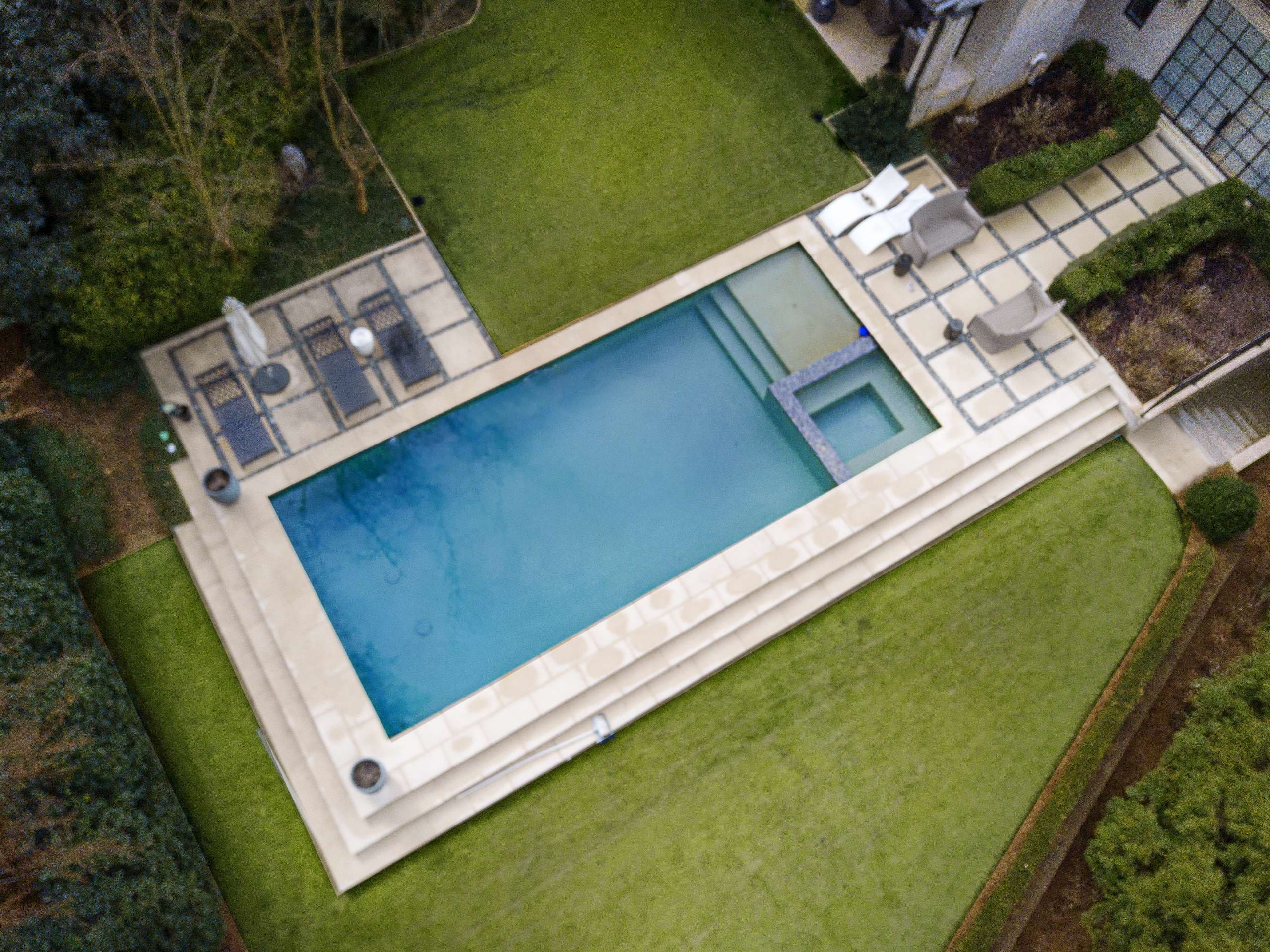 Rectangular pool with travertine coping and spa viewed from above in Metro Atlanta