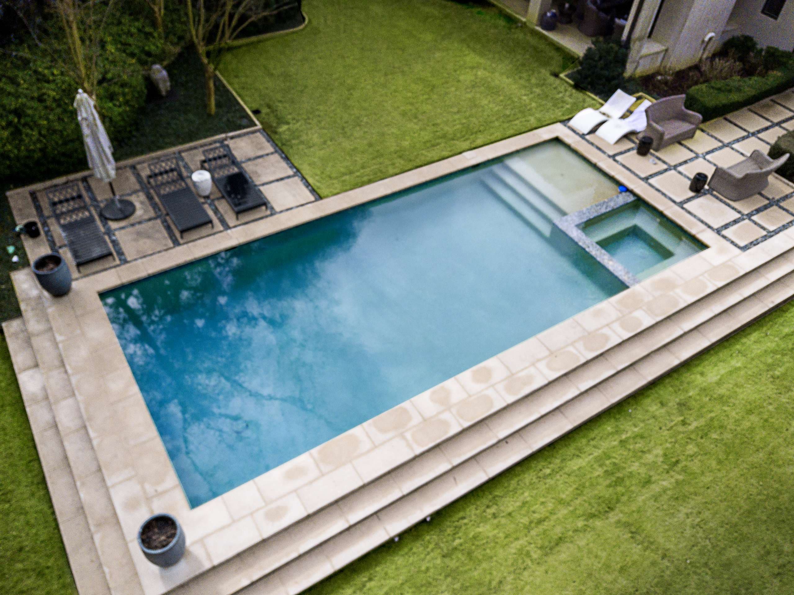 Rectangular pool with travertine coping and attached spa on residential property