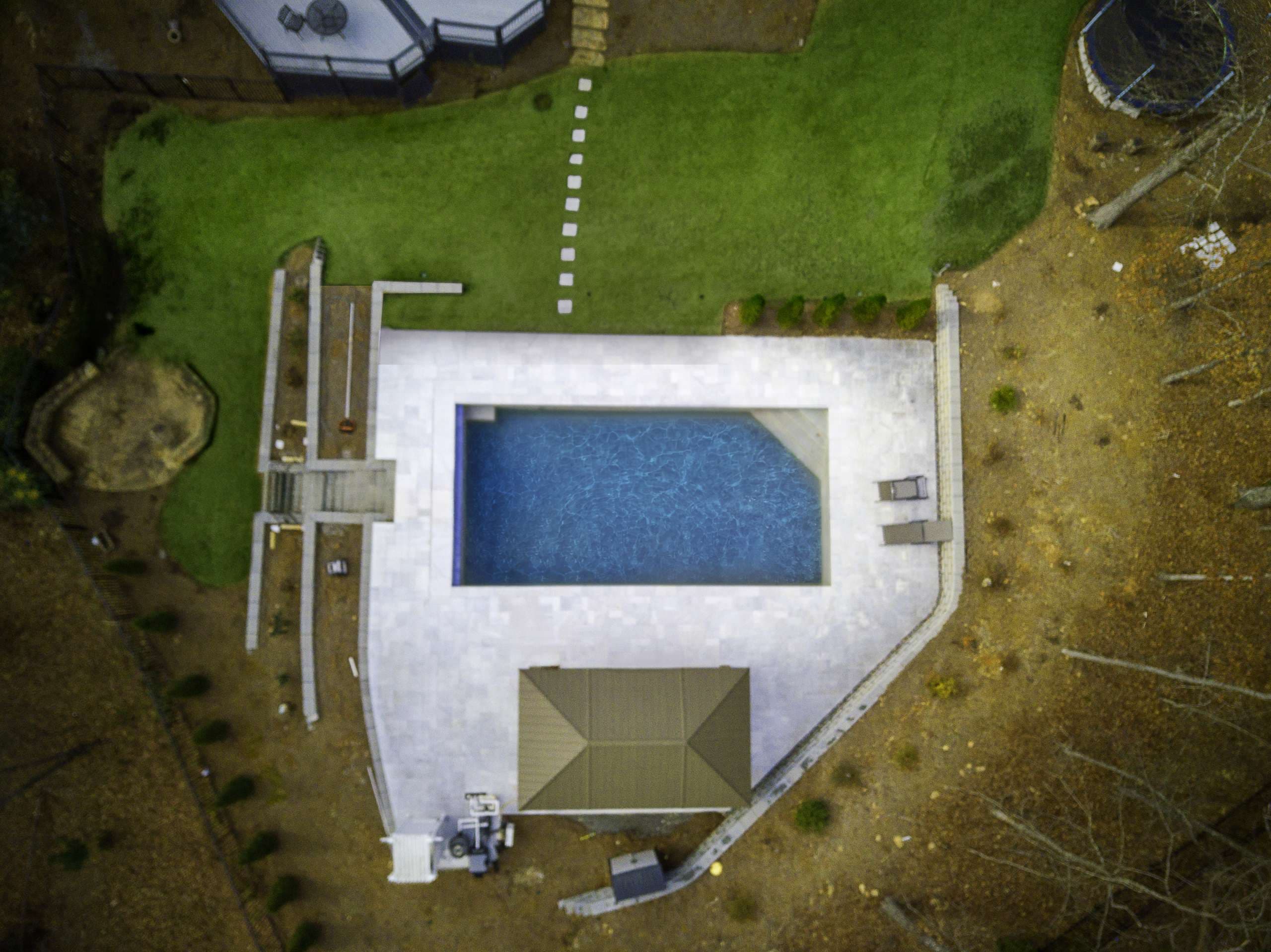 Rectangular pool with paver deck and covered pavilion on new construction property