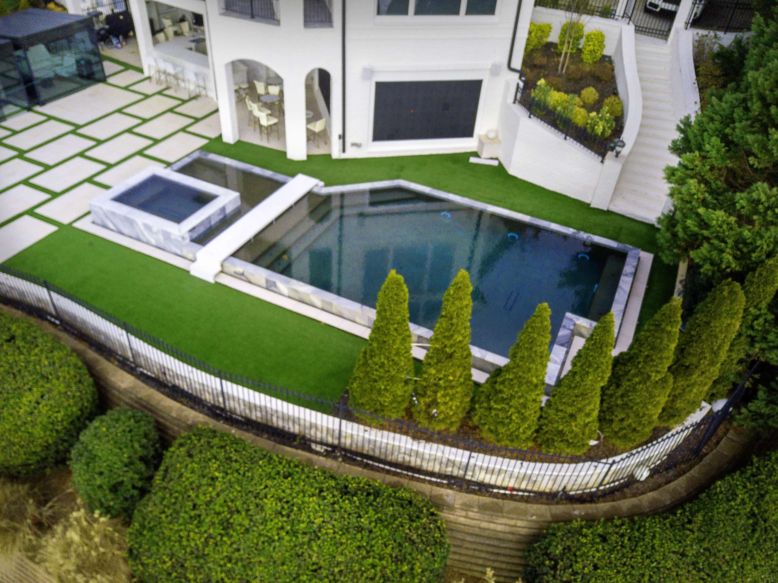 Modern pool and spa renovation with marble coping and Italian cypress landscaping