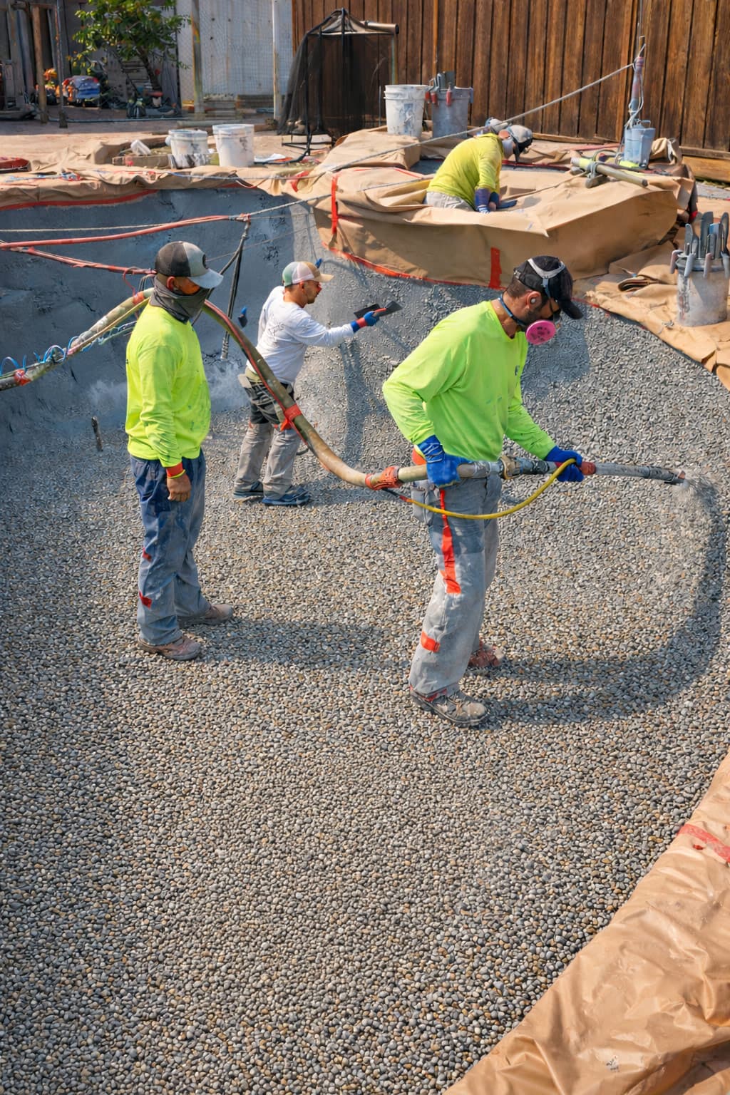 Pool resurfacing crew applying pebble finish to pool interior